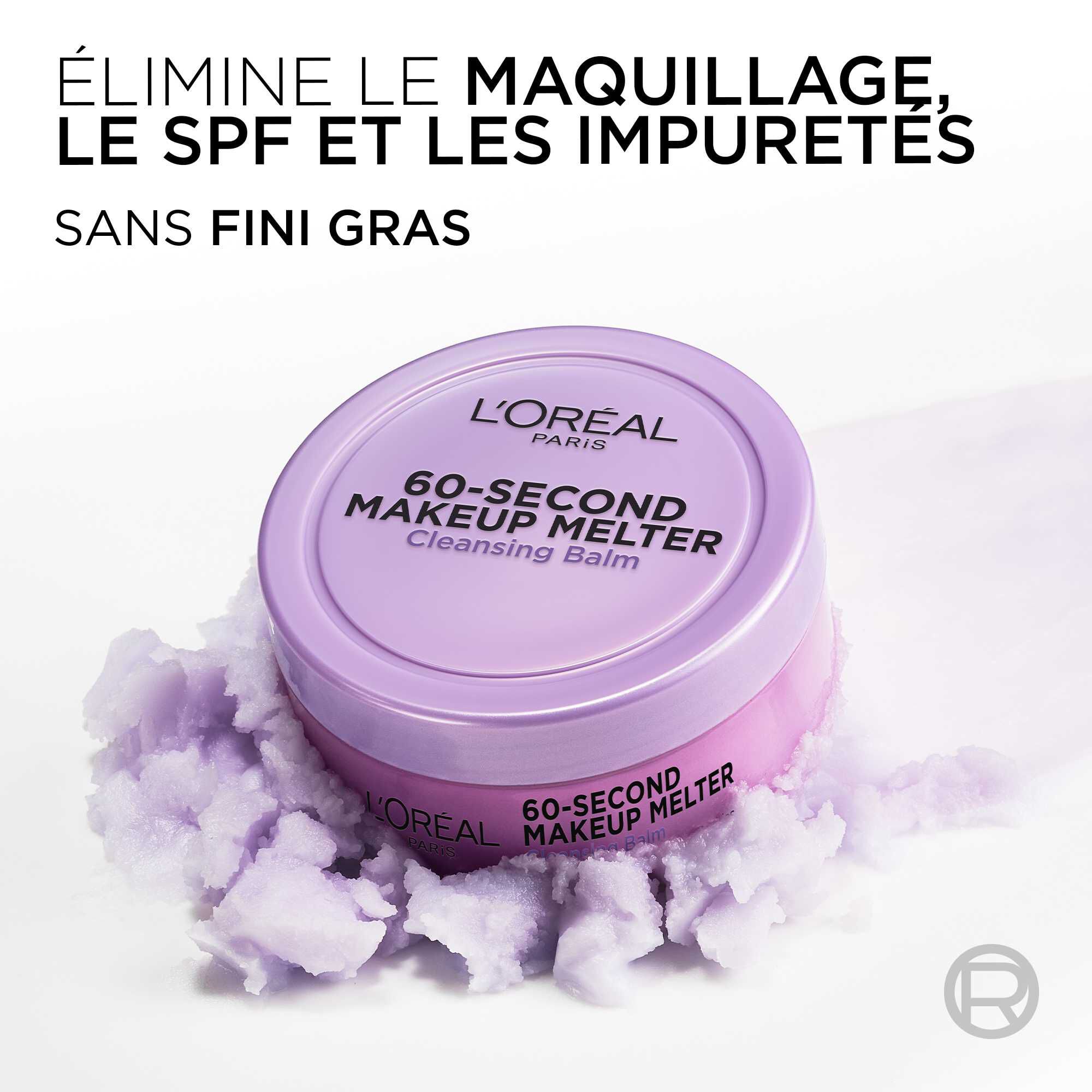 Le pot de baume demaquillant violet est pose sur une texture vaporeuse et violette rappelant un nuage de produit. Le texte en haut a gauche indique : « ELIMINE LE MAQUILLAGE, LE SPF ET LES IMPURETES SANS FINI GRAS ».