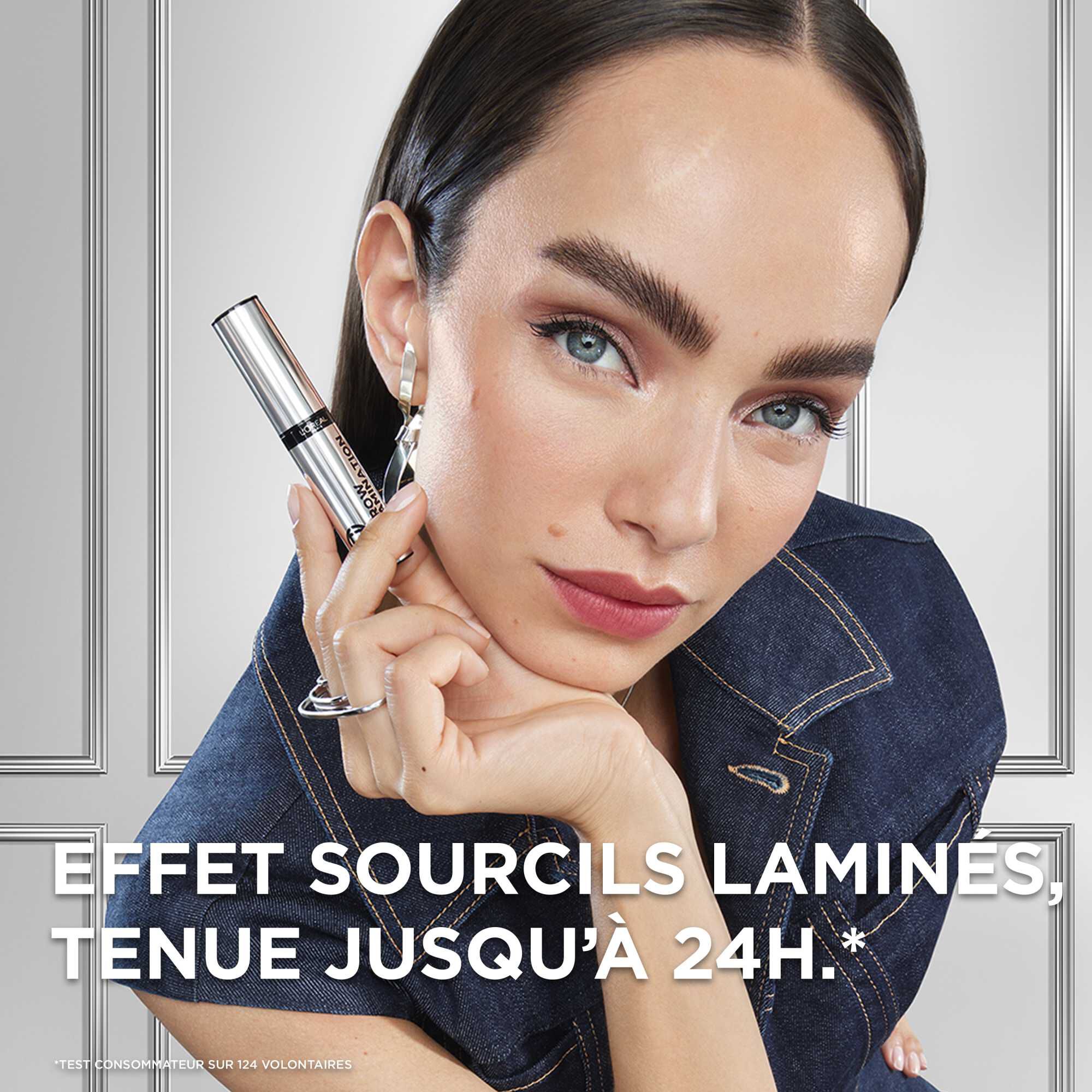 Portrait d'une jeune femme brune aux sourcils parfaitement disciplines, brosses vers le haut et fixes (effet lamine). Elle pose en tenant le flacon argente pres de son visage. Le texte en superposition indique : « EFFET SOURCILS LAMINES, TENUE JUSQU'A 24H.* »