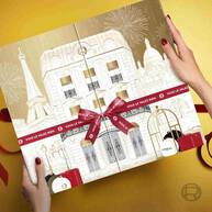Mains tenant le Calendrier de l'Avent L'Oreal Paris, montrant son design detaille de monuments parisiens et le ruban rouge.​