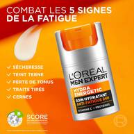 Le pot de L'Oreal Men Expert Hydra Energetic Soin Hydratant Anti-Fatigue 24H est place sur la droite. A gauche, une icone de goutte de produit est accompagnee de la liste des "5 SIGNES DE LA FATIGUE" que le produit combat : "SECHERESSE", "TEINT TERNE", "PERTE DE TONUS", "TRAITS TIRES" et "CERNES". En bas a gauche, un "SCORE ENVIRONNEMENTAL" de categorie B est affiche. Le fond est un degrade de blanc et d'orange.