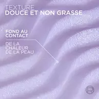 Gros plan texture sur le baume de couleur violette, montrant des vagues cremeuses et douces. Le texte superpose indique : « TEXTURE DOUCE ET NON GRASSE » et une fleche precise « FOND AU CONTACT DE LA CHALEUR DE LA PEAU ».