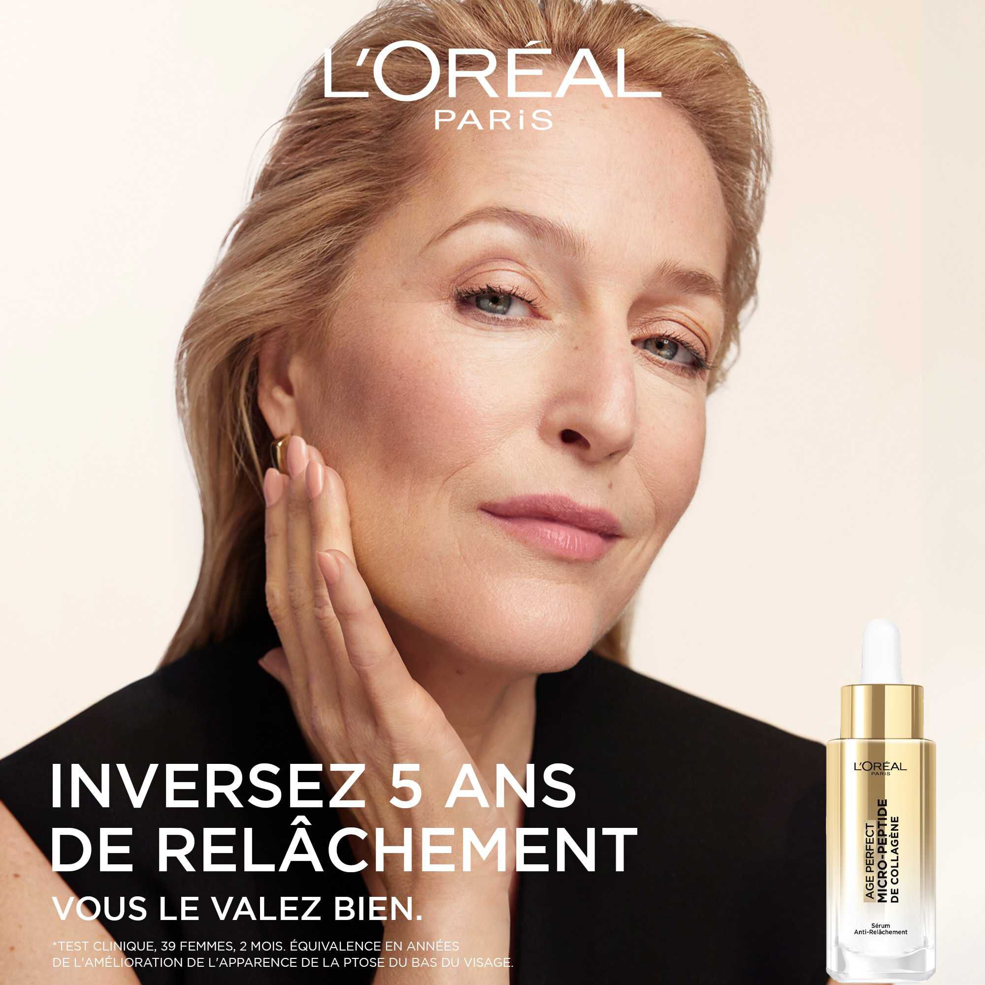 Femme mature souriante, visage apaise, posant avec le serum L'Oreal Age Perfect Micro-Peptide de Collagene et le slogan "INVERSEZ 5 ANS DE RELACHEMENT. VOUS LE VALEZ BIEN.".