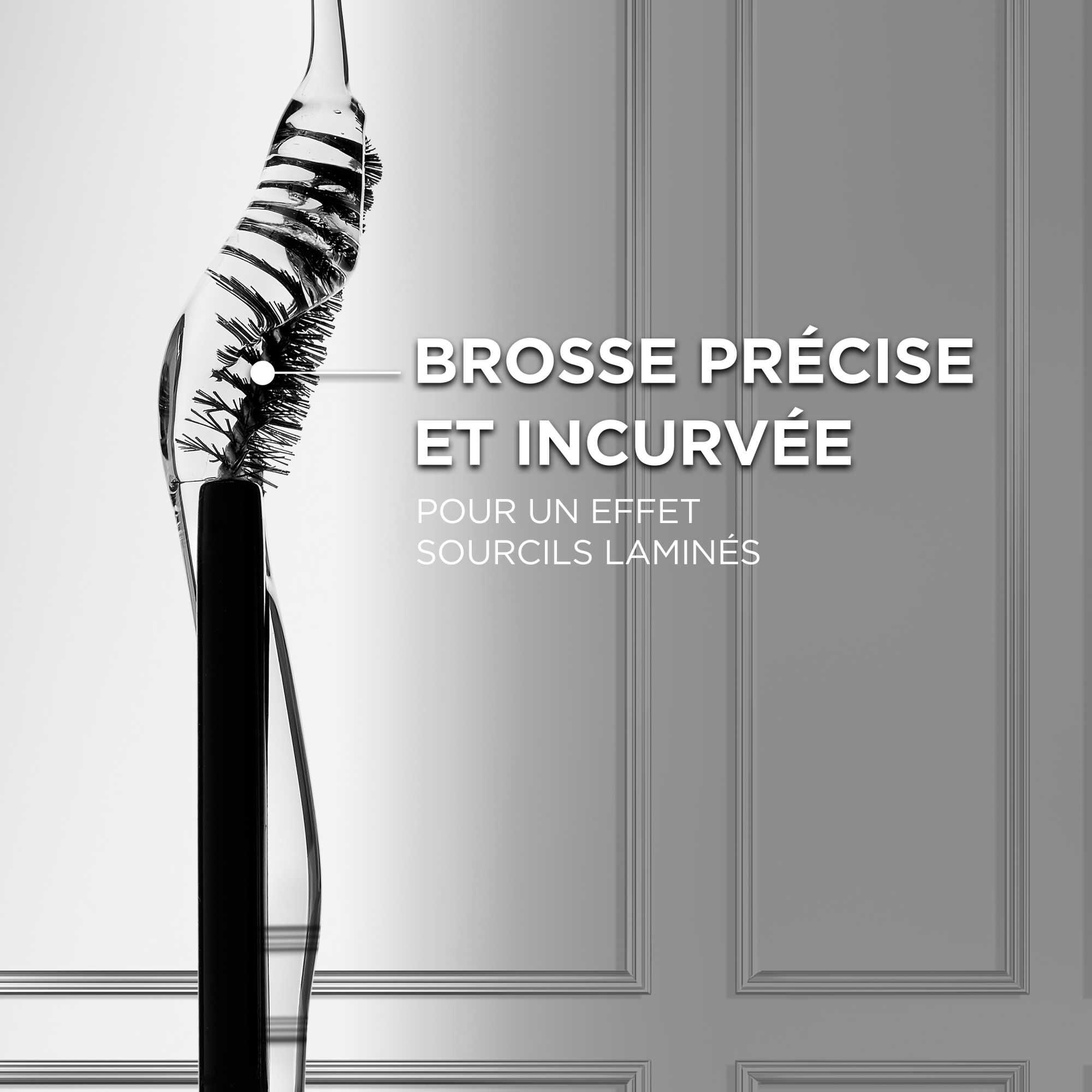 Macrophotographie en noir et blanc de la brosse applicatrice incurvee, montrant la precision de ses picots asymetriques concus pour attraper chaque poil. Le texte explicatif indique : « BROSSE PRECISE ET INCURVEE POUR UN EFFET SOURCILS LAMINES ».