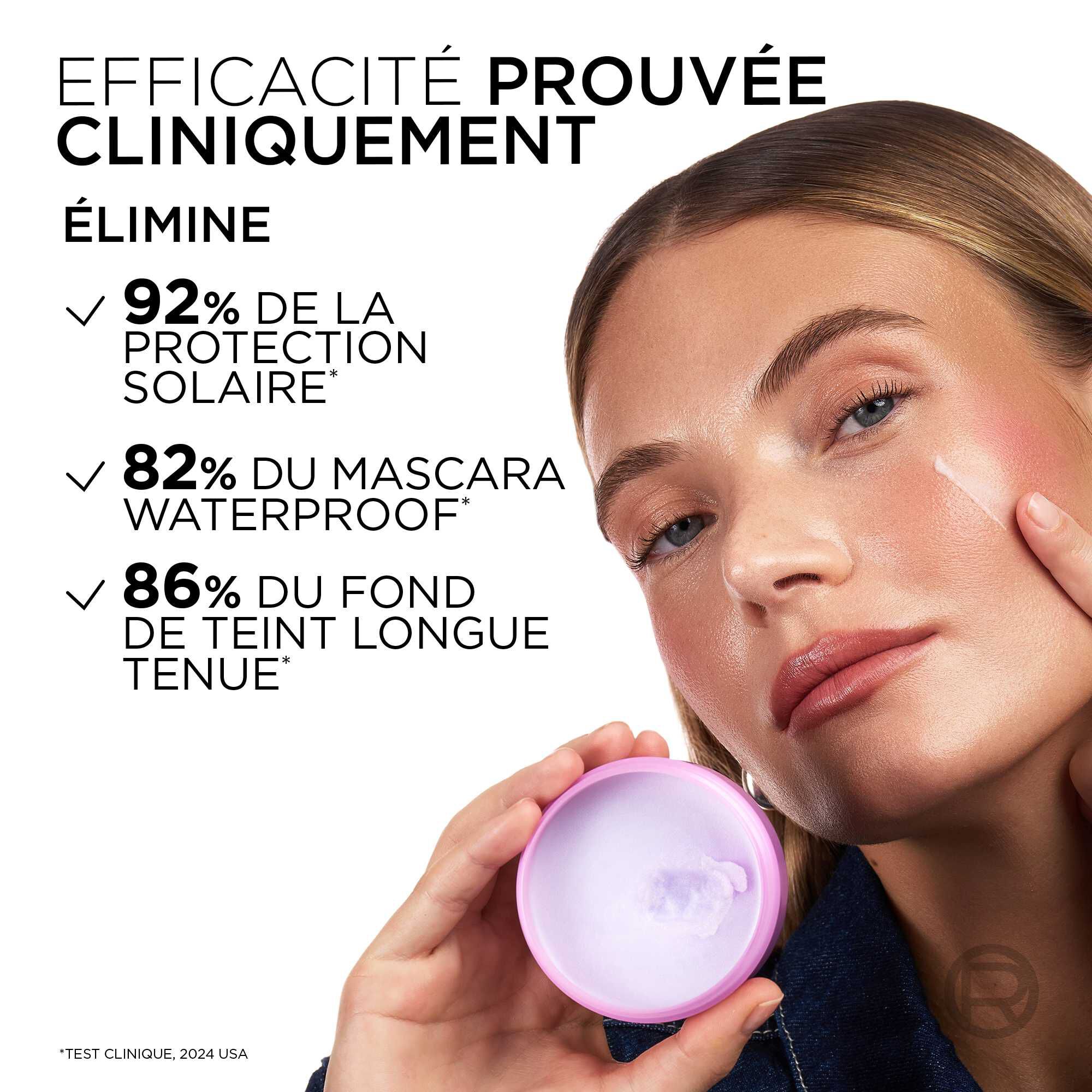 Une mannequin tient le pot de baume demaquillant ouvert, revelant sa texture solide blanche a l'interieur. A gauche, les resultats cliniques sont listes : « EFFICACITE PROUVEE CLINIQUEMENT. ELIMINE : ✓ 92% DE LA PROTECTION SOLAIRE*, ✓ 82% DU MASCARA WATERPROOF*, ✓ 86% DU FOND DE TEINT LONGUE TENUE* ».