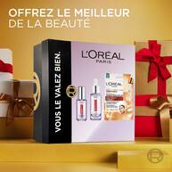 Coffret cadeau L'Oreal Paris Revitalift Filler pose dans un decor de cadeaux de Noel emballes avec des rubans rouges. Le coffret affiche "L'Oreal Paris Vous le valez bien"​