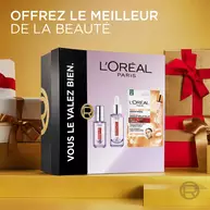 Coffret cadeau L'Oreal Paris Revitalift Filler pose dans un decor de cadeaux de Noel emballes avec des rubans rouges. Le coffret affiche "L'Oreal Paris Vous le valez bien"​