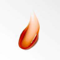 Gouttelette de gel orange-rouge brillant, avec une texture gelatineuse et translucide, posee sur une surface blanche reflechissante.