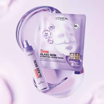 Image representant Charlotte Cardin pose a cote d'un serum et d'un masque L'Oreal Revitalift Glass Skin sur un fond violet clair.